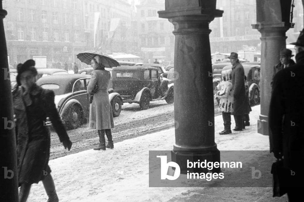 Several people are walking through the snowy city