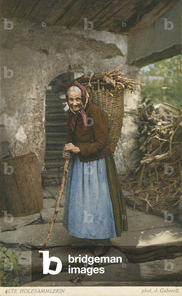 Vecchia donna che raccoglie legno (foto a colori)