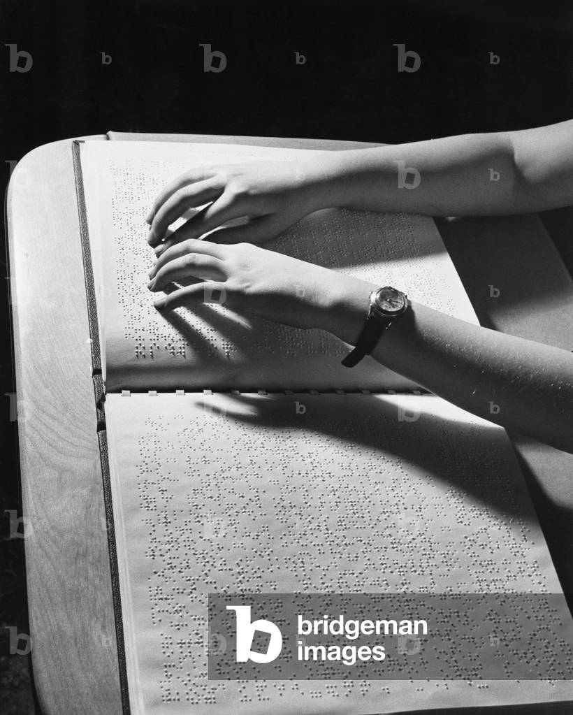 Vista dall'alto delle mani di una ragazza che legge in Braille