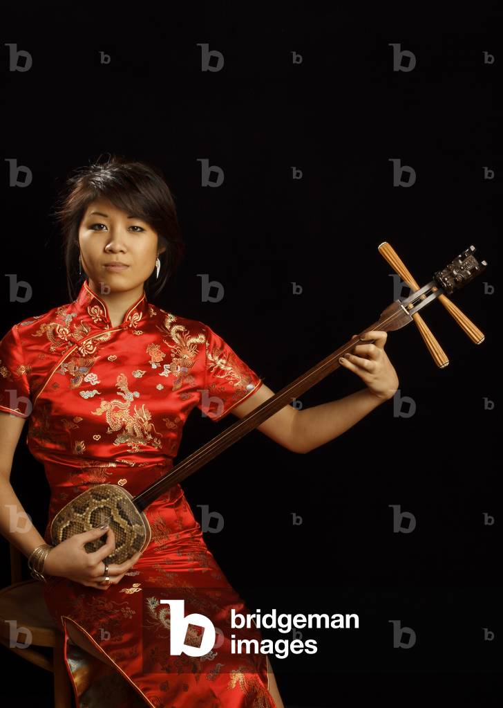 Chinesisches Mädchen hält ein San Hsien oder Sanxian