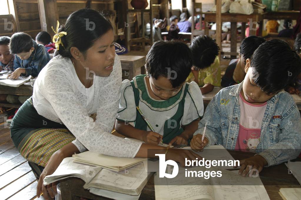 Image of Photography depicting A female teacher assists young children to solve mathematics equation in grade 