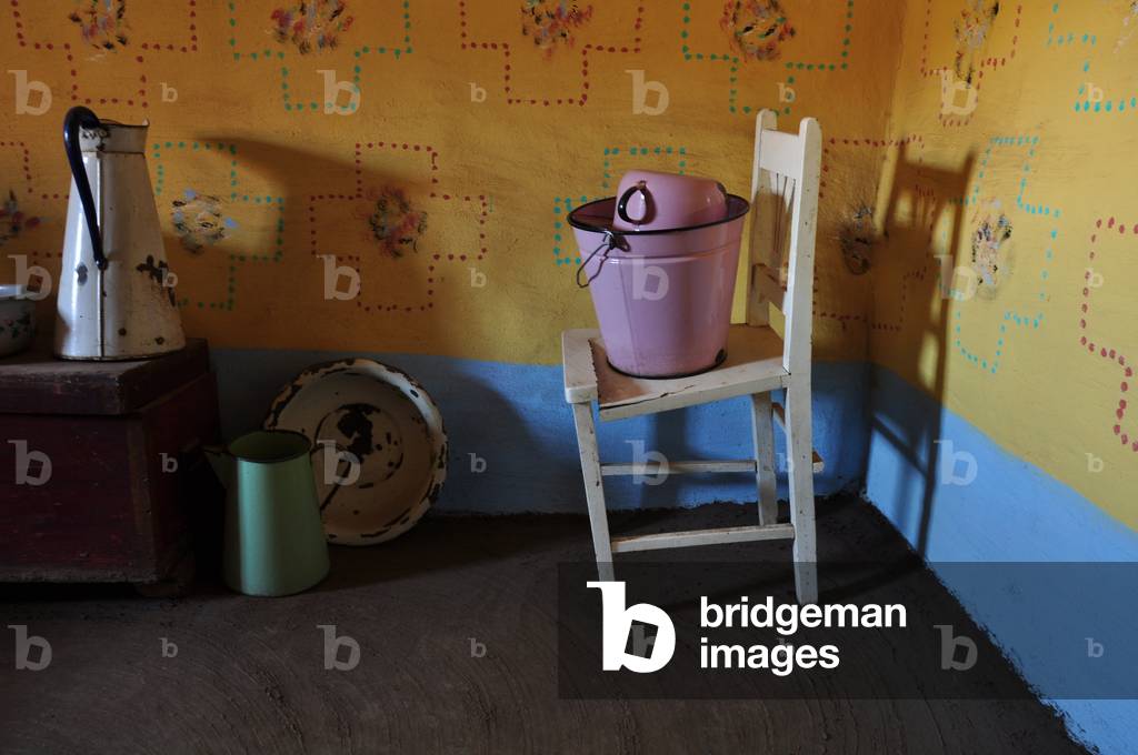 Ein viktorianischer Badekrug auf einem alten Stuhl in einem Basotho-Haus, der den Einfluss europäischer Siedle