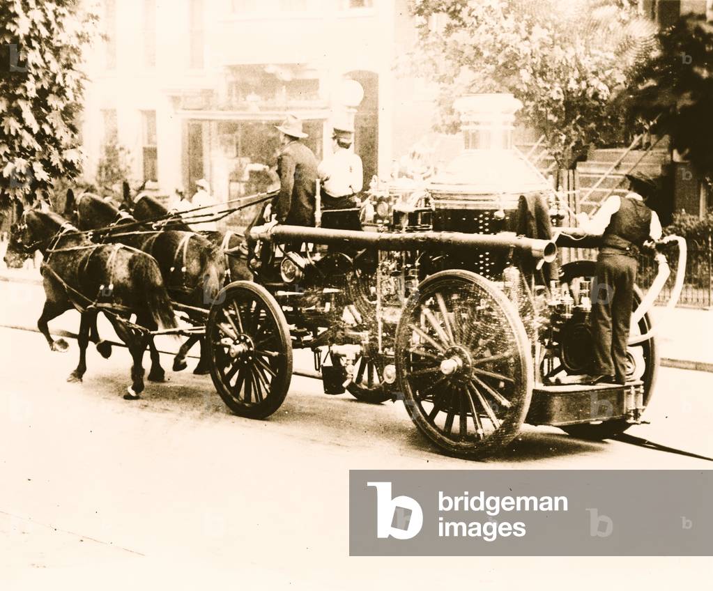 Immagine di Fotografia "Tre pompieri sul motore dei pompieri trainati da tre cavalli", b/w