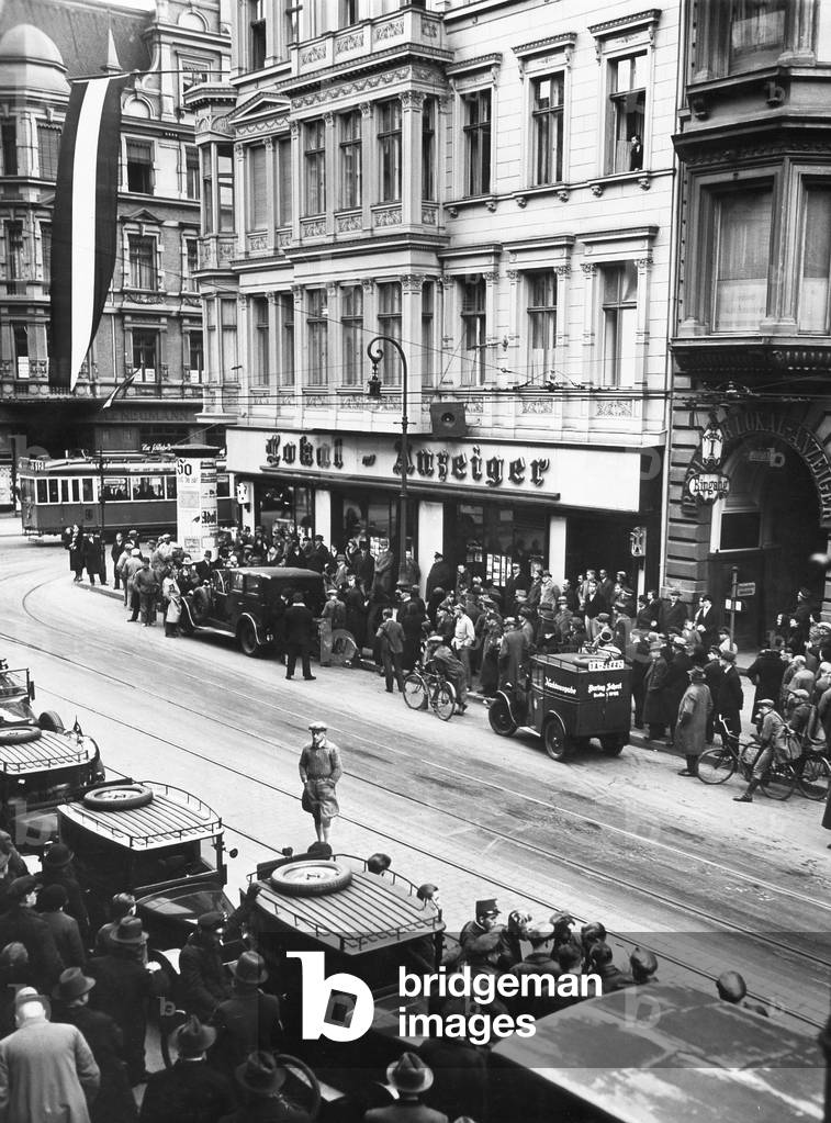 Image of Photography depicting Pedestrians listen to a speech of Hitler 1933, b/w