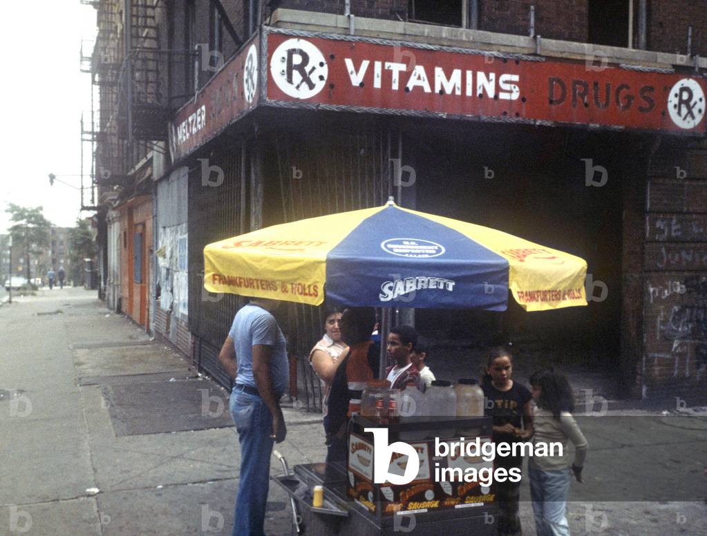 "Venditore di hot dog nel South Bronx infront of burn out shops and tenement block"