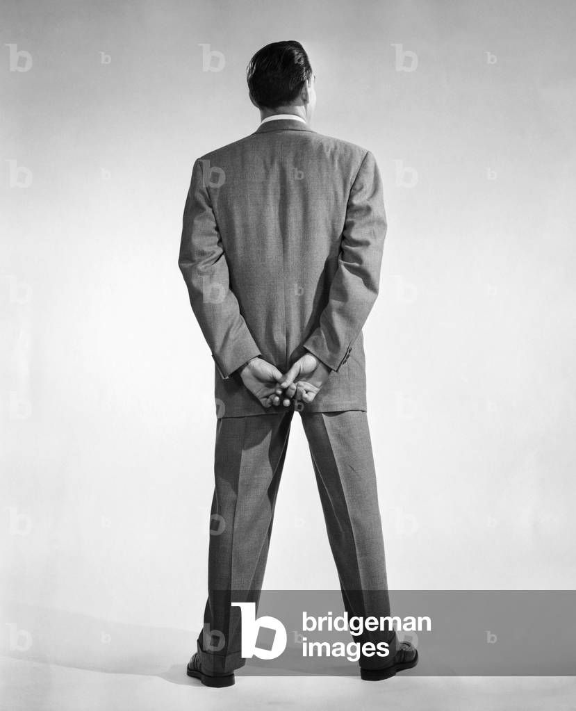 Rückansicht eines Mannes, der mit den Händen hinter dem Rücken steht