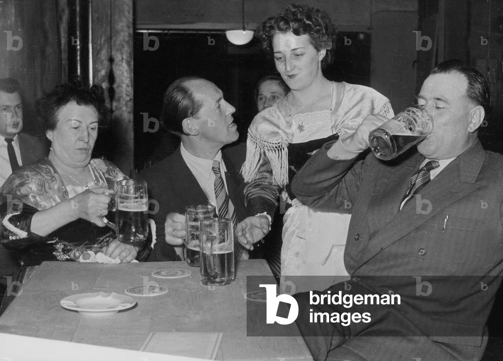 Una cameriera porta birra agli ospiti in un pub bavarese di Amburgo Reeperbahn, anni '50