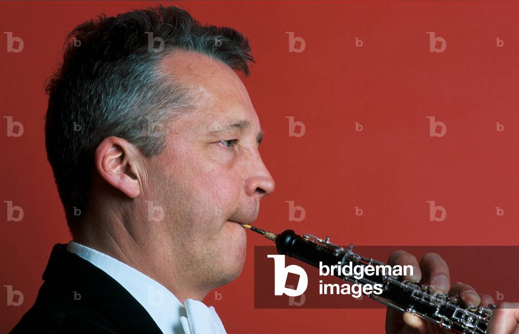 Image of Photography depicting Man playing oboe against by Chris Stock