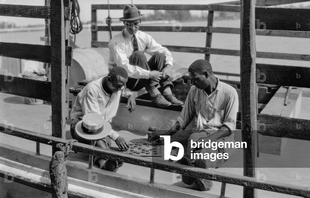 African-American men, apparently deckhands on a boat, play checkers and are observe..., 1929 (photo)