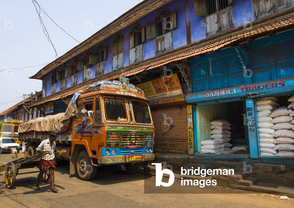 Immagine di Fotografia "Camion dipinto parcheggiato davanti a una casa colorata nella via commerciale di Kochi