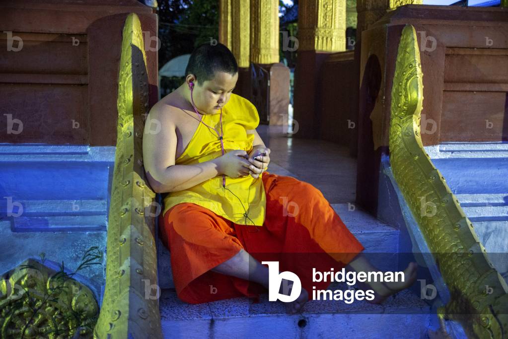 Young Monk with a mobile phone in Wat Sensoukaram buddhism temple in Luang Prabang city, Laos (photo)