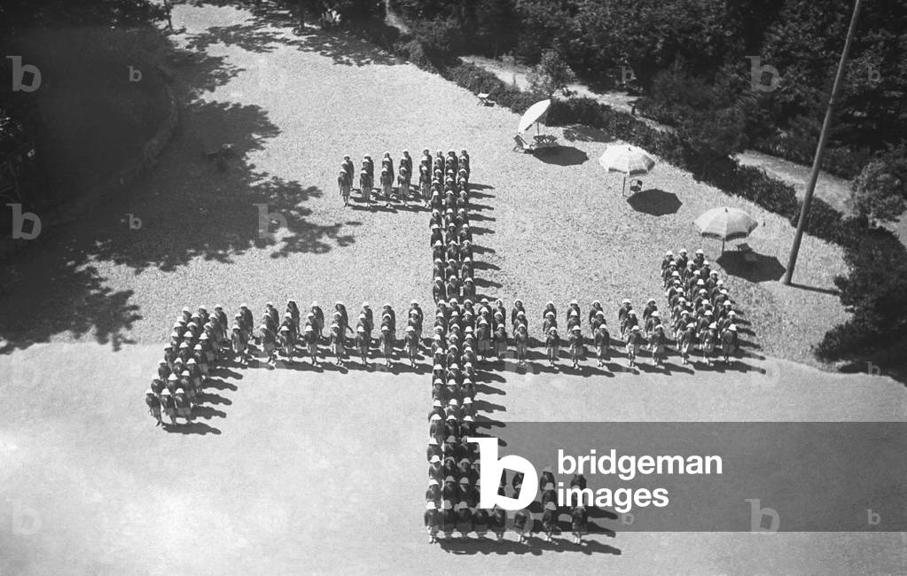 Image of Piccole Italiane at summer camp making up Nazi swastika, August