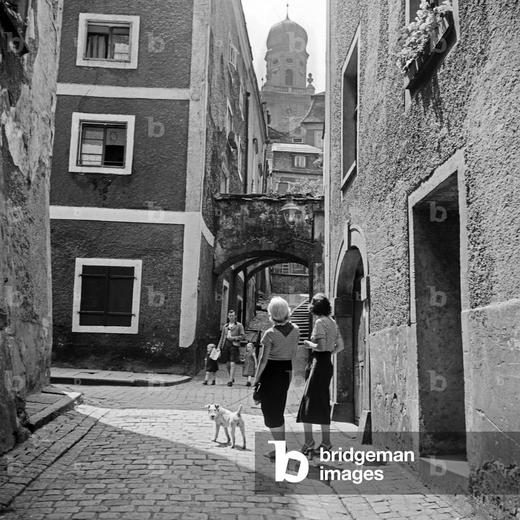 Image of Photography depicting Two women and their dog strolling through a small lane of Passau with direction