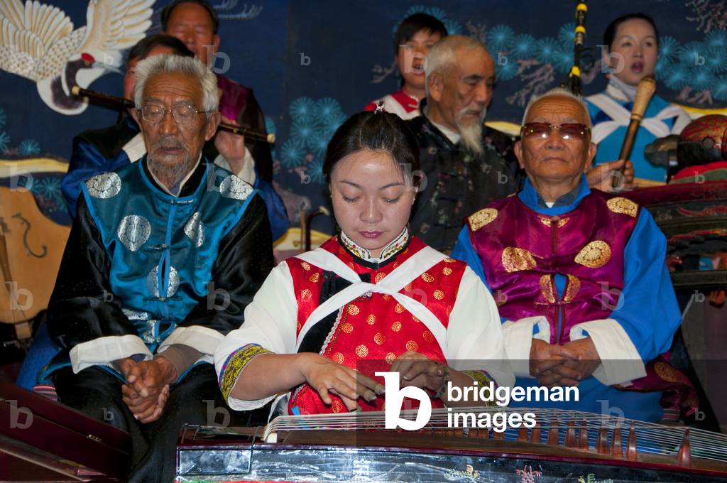 Image of Photography depicting China: A woman plucks a guzheng