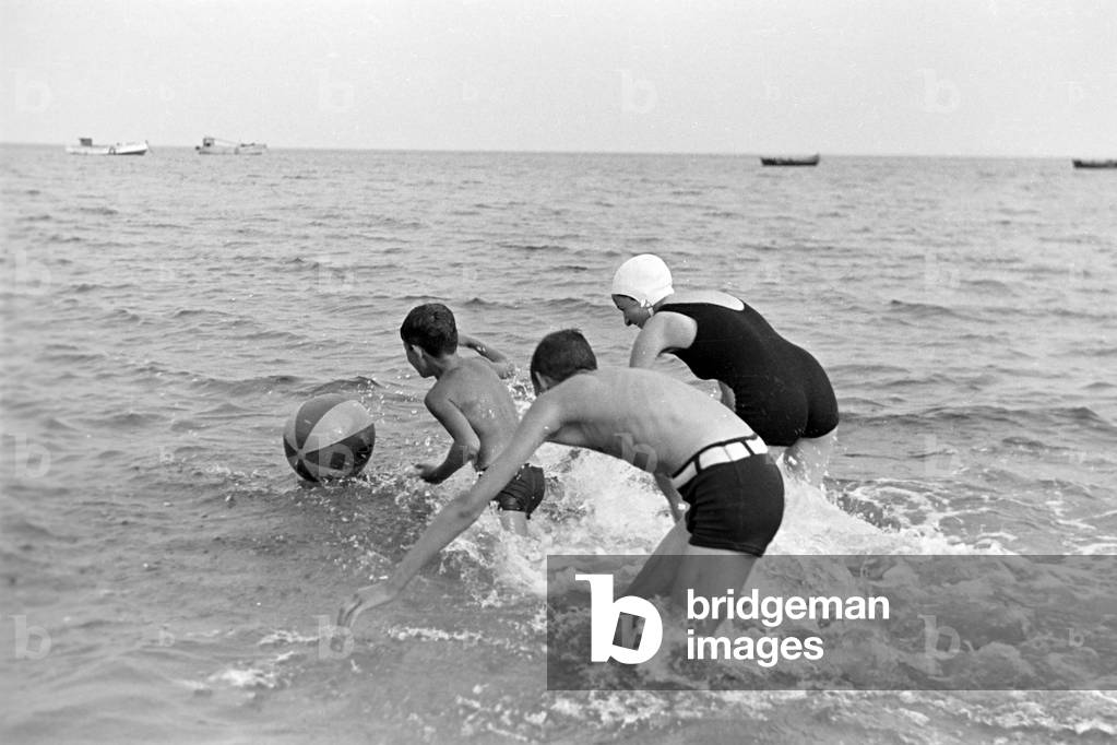 "Eine junge Frau und zwei Jungen toben durchs Wasser" 1939