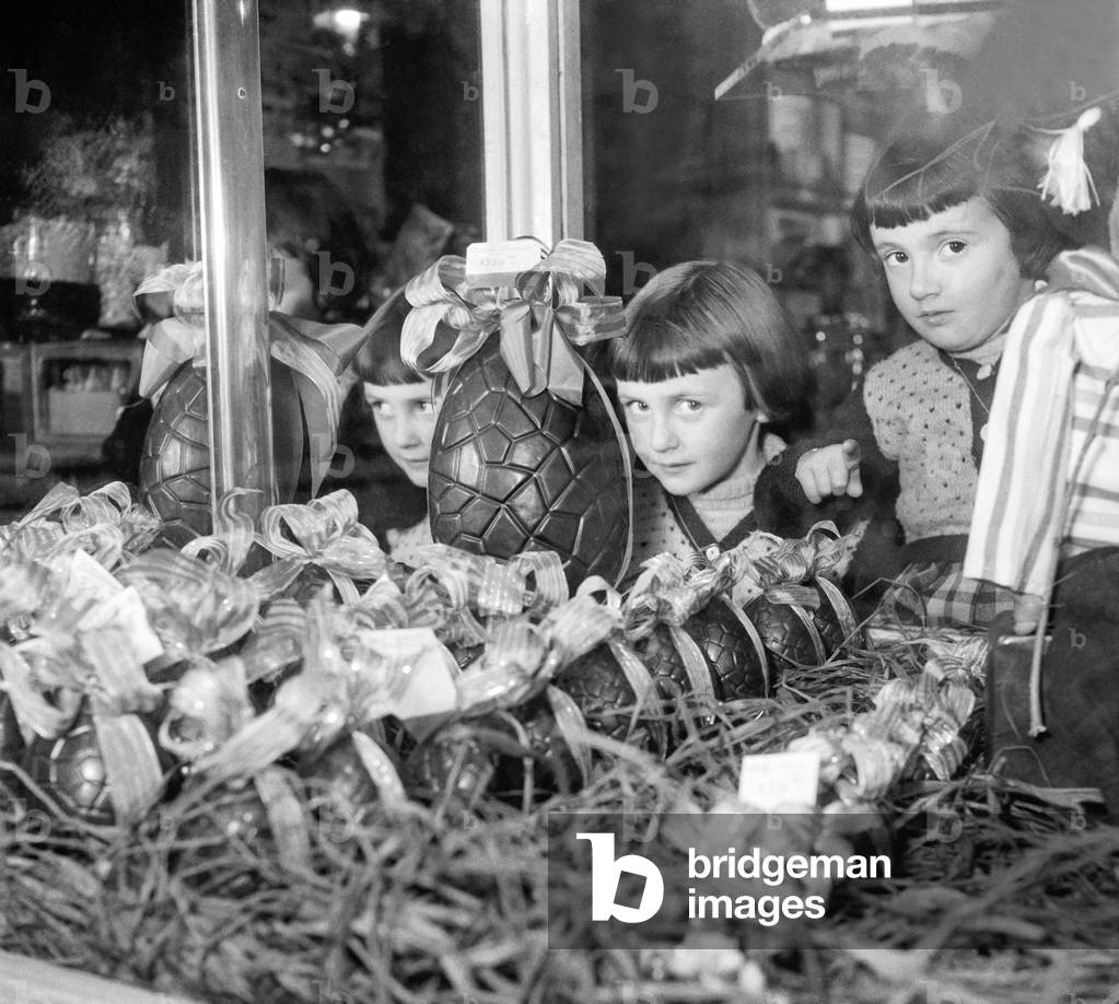 Image of Photography depicting Children looking at Easter eggs (chocolate) in a shop window 1951, b/w
