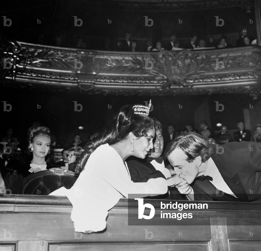 Franco Zeffirelli kisses Elizabeth Taylor's hand in front of Richard Burton at the Opera de Paris, 1967 (photo