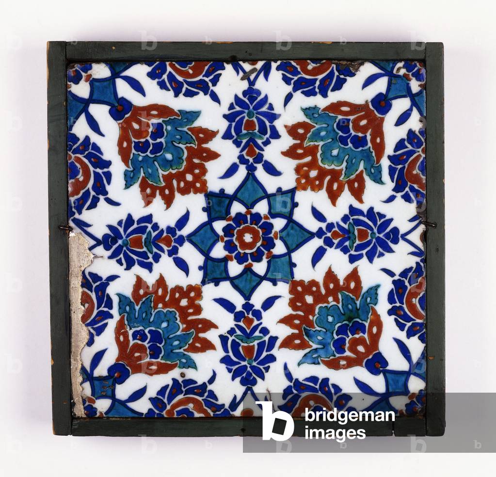 An Iznik pottery tile, with a symmetrical design of four red and green palmettes around a central stellar flow
