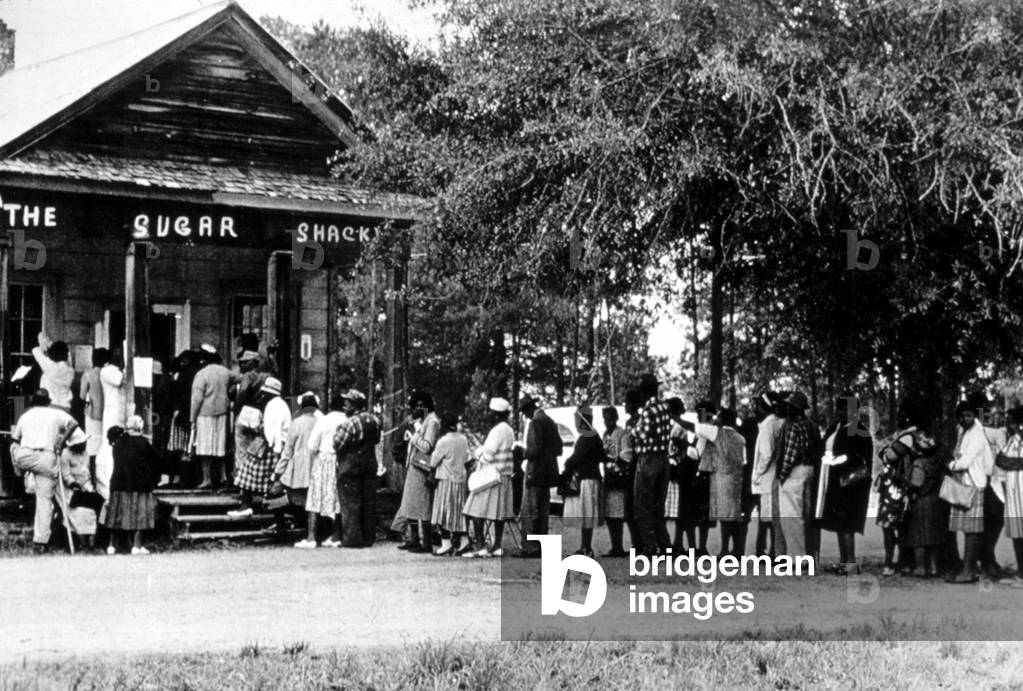 Image of African Americans line up to vote at store in Alabama