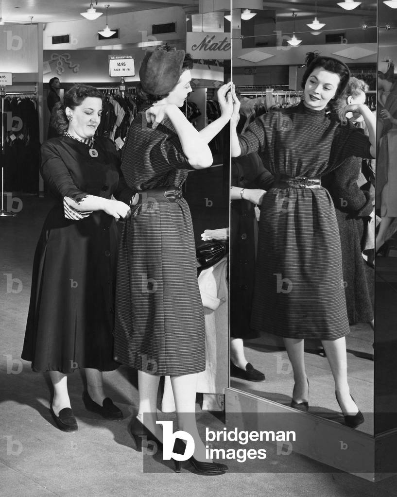 Immagine di Fotografia "Giovane donna che prova vestiti in un negozio di abbigliamento e una donna di mezza et