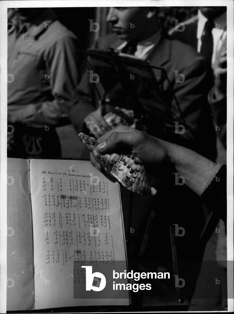 May 05, 1953 - Large and small shells are used by German missionaries with the papuas on New-Guinea to replace organs. They are blowing chorales on them. They are also using a special sound and note-syste invented by them as there may only one sound be blown on one shell. The shell - chorus being similar to the trombon- ~ ~ ~ ~ in its sound can, on the whole world, be found on two places ~ ~ ~ ~ ~: in New-Guinea (the second largest island in the world in the North of Austrlia) and in the Middle-Frankonian place Neuendettelsau where there is a training - school for missionaries. At the occasion of the looth anniversary of the foundation of the Menendettelsau institution the shell-chorus gave a special performance for the present guests. Our picture shows some scene of the chorus with the shell. the largest of which has the size of an adult person.