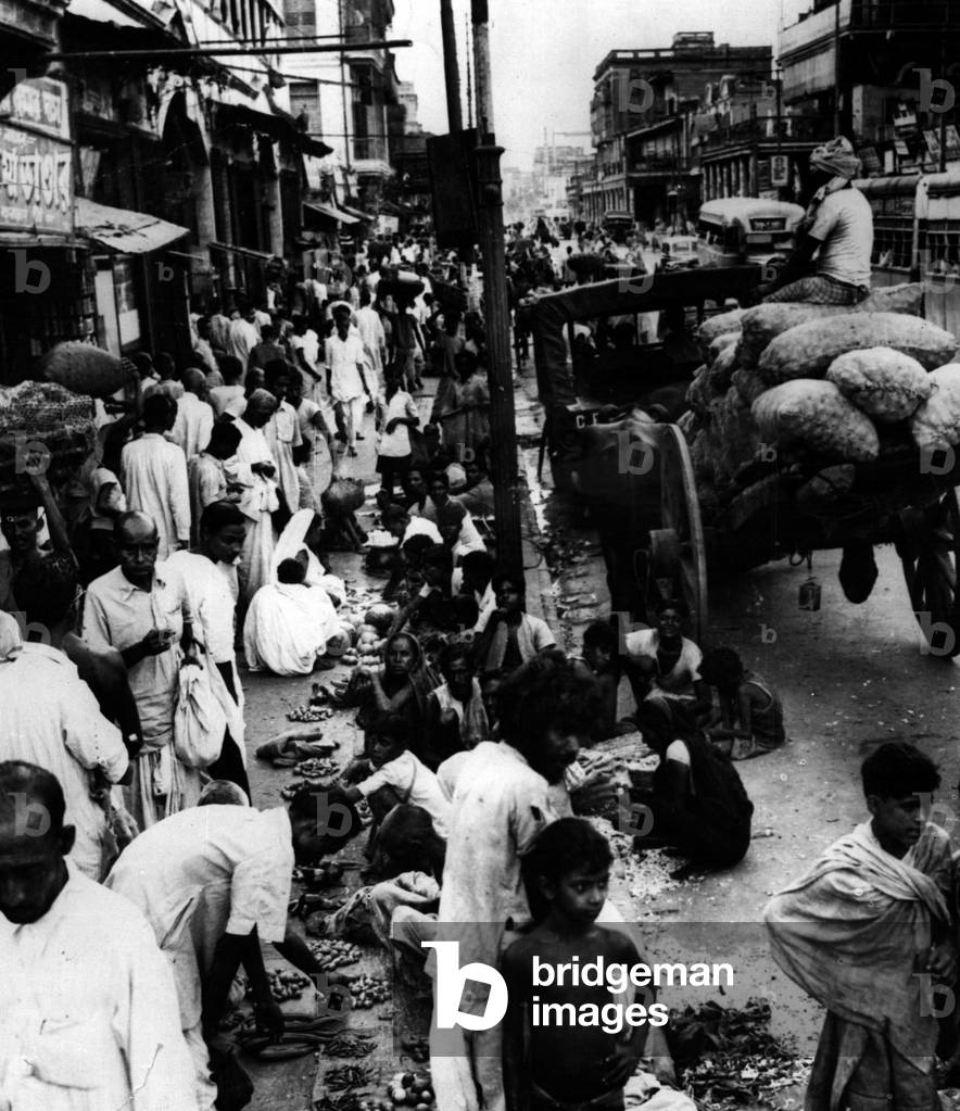 Jan. 01, 1955 - Wholesale retailing in Kolkata: Calcutta today is largely a city of congestion and overcrowding but nowhere so conspicuously as in Bowbazar. This picture shows the street during a comparatively quiet time of the day with vegetable retailers selling their goods on the pavement outside the big wholesale vegetable market near Sealdah Railway Station. In the evening, when thousands of office workers make their way to the station on their way home - the pavement becomes almost impassable
