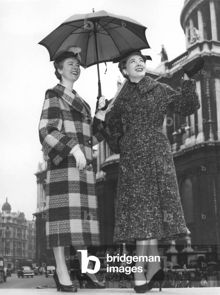 May 03, 1954 - London, England, United Kingdom - SHELAGH (L) wears a fancy Cooks of St. Paul's Collection checked coat in grey and gold and VERONICA wears a fancy knotted tweed coat in grey and rust as they show off Cook's Fall and Winter styles