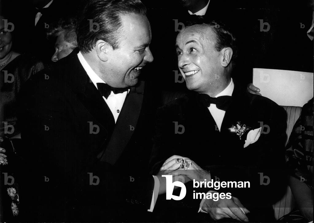 May 24, 1954 - Stocking king Thierfelder and fashion king Schuberth, one from Germany the other from Italy, are seen here in conversation. The ring on Emilio Schubert's hand and the trinket on his lapel are definitely noticeable. He is showing that these things aren't just for women