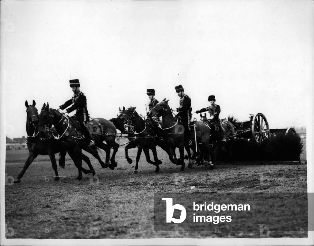 Apr. 04, 1953 - King's Troop of The R.H.A. Rehearse... Even The Gun Goes Over The Hurdle.. The King's Troop of the Royal Horse Artillery was to be seen rehearsing at Wormwood Scrubbs for their public shows this year. A new manoeuvre is carried out by six horses with limber and a thirteen pounder gun - in which they charge over a three foot brushwood fence.. The lead, middle and wheel horses jump independently - the gun and limber being dragged over the fence.. Keystone Photo Shows: - The scene as the team of six, complete with gun ans limber - take the brushwood hurdle at Wormwood Scrubbs.