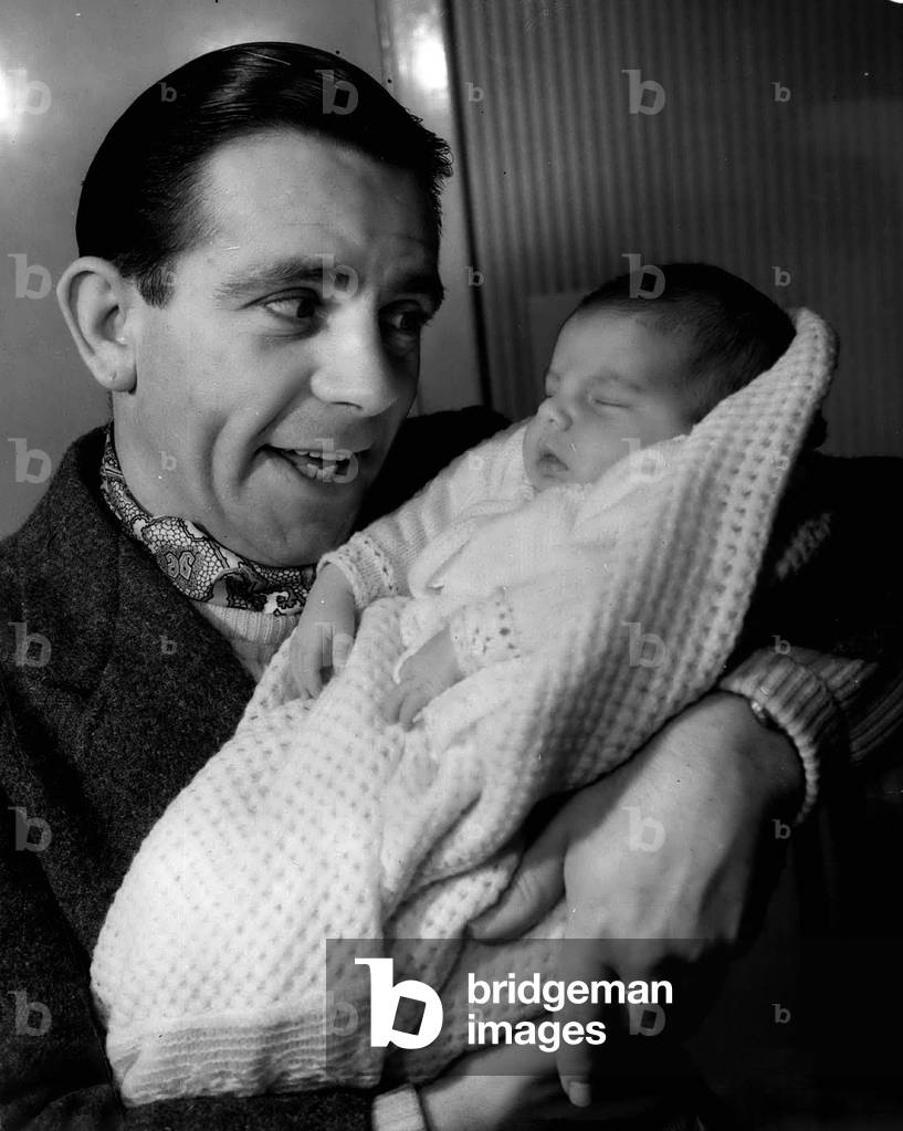 Jan. 01, 1955 - Norman Wisdom And Baby Jacqueline: Photo Shows Famous Comedian, Norman Wisdom, seen as he tenderly holds his baby daughter, Jacqueline - at his Barnet home