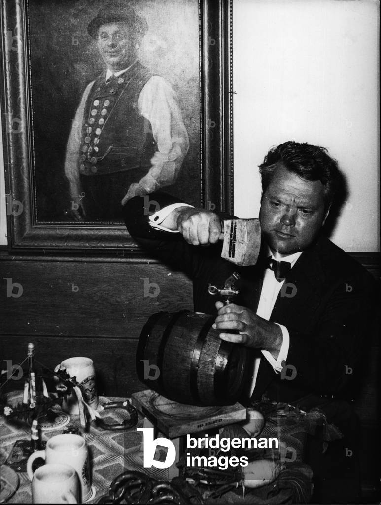 May 05, 1954 - A cask of beer... the terrible enfant of Hollywood Orson Welles, tapped in the Munich” beer inn”” Platzl” well known all about the globe, by himself, after having finished his film work near” Hofbrauhaus”. Cause of his Munich stay is his latest picture” Mr. Arkadin”, in which Marlene Dietrich herself plays a mainpart. The Munich beer tasted Orson Welles very good. As a matter of fact there couldn't be a original Munich meal without” Brezn” and” Radi”. Down from the wall the former Minich folks - clown Weiss Ferdl wtched the seen who fascinated for years the strangers from abroad, on the stage of the” Platz '