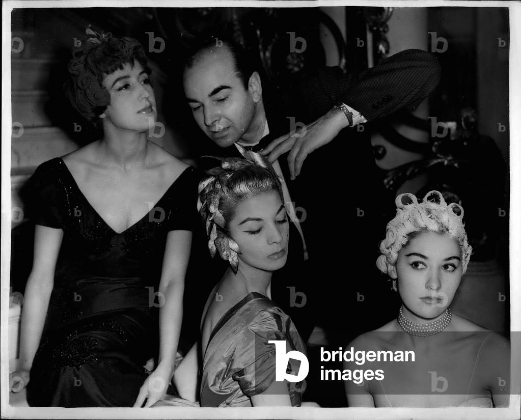 Tue. 03, 1954 - Famous French hair stylist shows his new designs: M. Jean Clement the famous French Hair stylists was to be seen at the Salon of Beauty 45 Park Lane this evening demonstrating some of his newest styles.: Photo shows M. Clement with three of the young ladies and the styles this evening. They are L-R: Olga Patterson wearing” Midnight Devil”; Peggy Curtis wearing” Versailles” and Jeanna Foslow wearing” Megeve”. M. Clement has dressed the hair of many famous persons including ex-King Farouk; Queen Juliana of the Netherlands; Barbara Button and Lily Pons